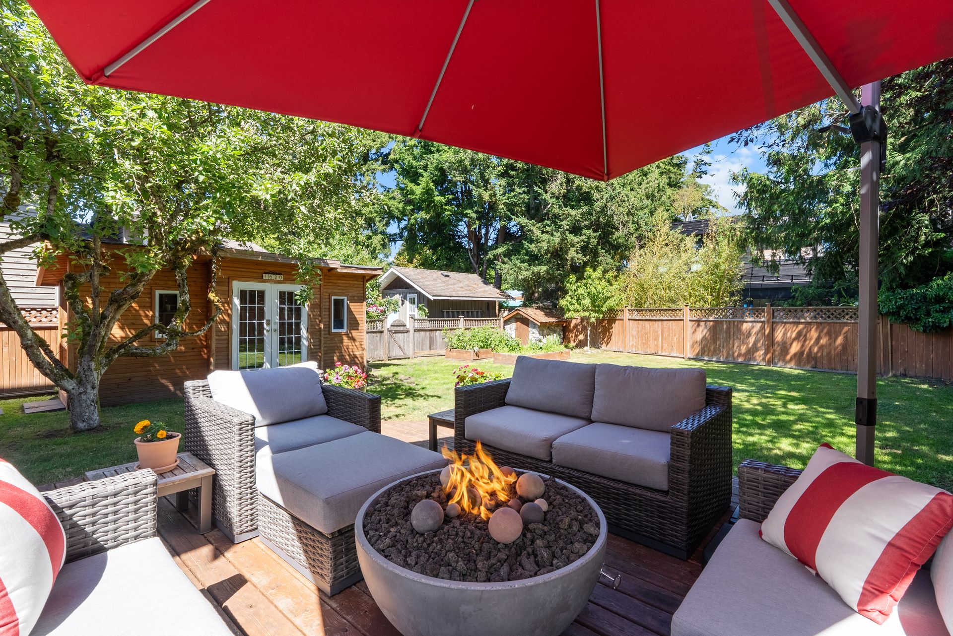 Patio with a red umbrella and a fire table